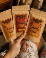 Hands holding three Brew Your Sip CTC chai sampler pouches