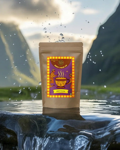 Brew Your Sip's First Flush tea leaves package with a colourful label on a reflective water surface with mountains in the background