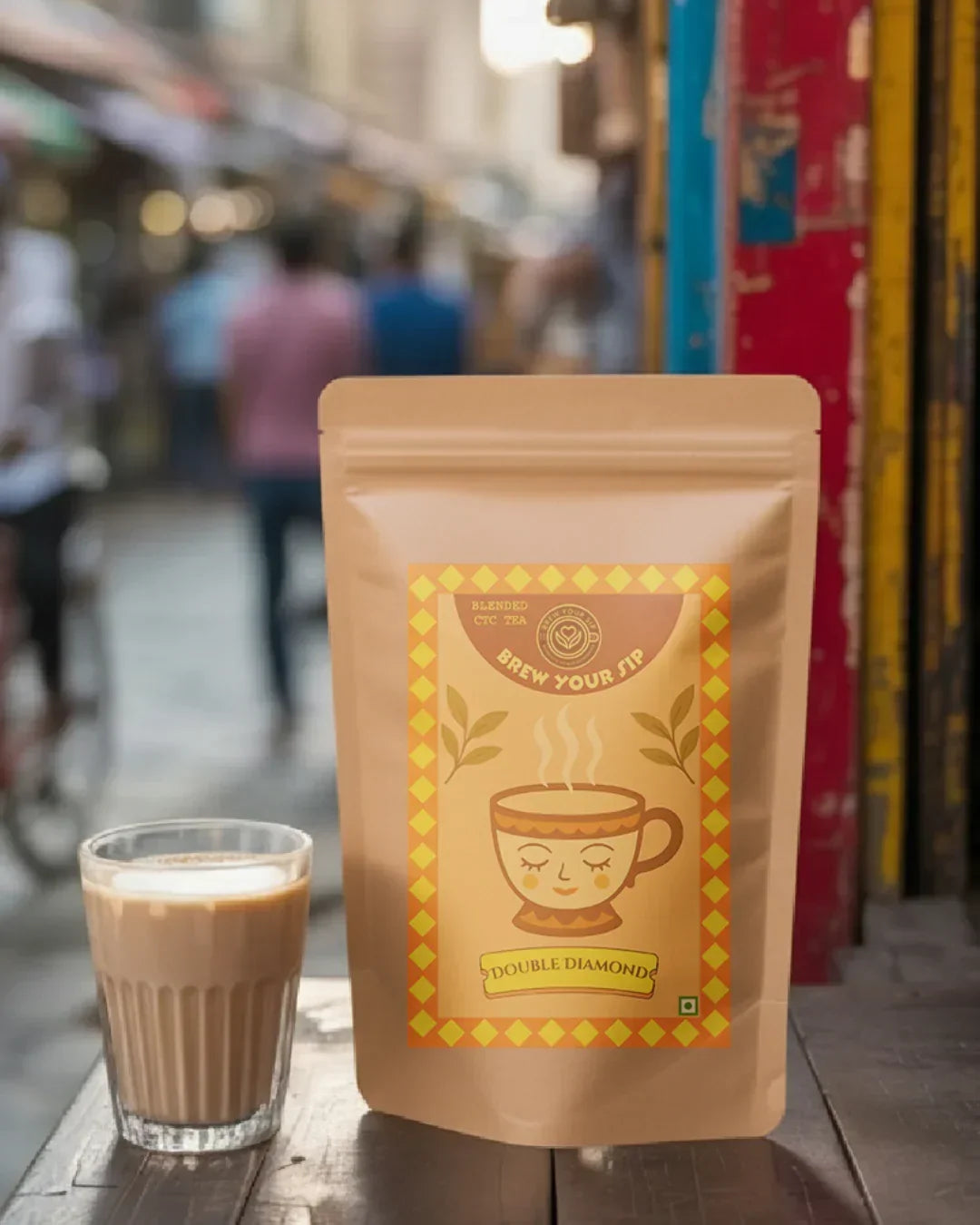 Tea pouch with a label and a glass of tea on a wooden surface, blurred street scene in the background