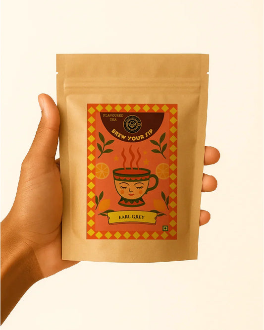 Hand holding a package of Earl Grey tea with a decorative label on a beige background