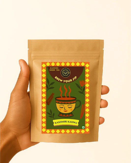 Hand holding a brown package of Kashmiri Kahiwa with a colorful label on a beige background