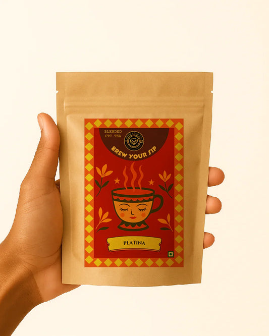 Hand holding a brown tea package with a red label featuring a cartoon cup and text on a beige background