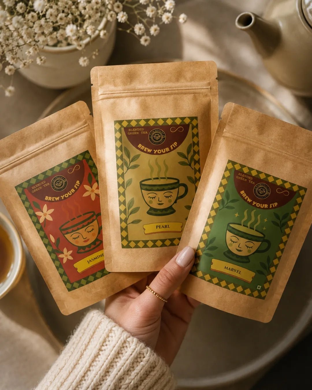 Hands holding three Brew Your Sip green tea sampler pouches